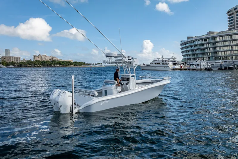  Yacht Photos Pics 2021 Yellowfin 26 Hybrid boat cruising near marina with modern buildings in background.