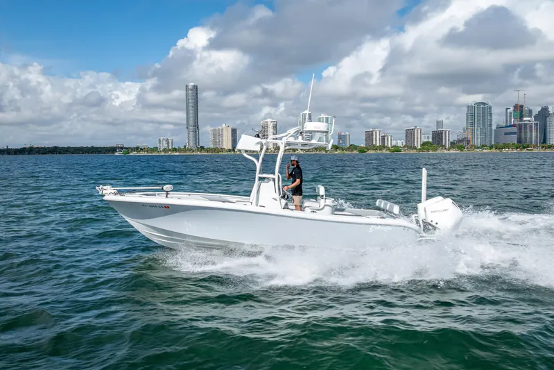 Yacht Photos Pics 2021 Yellowfin 26 Hybrid boat cruising near city skyline on a sunny day.