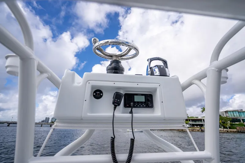  Yacht Photos Pics 2021 Yellowfin 26 Hybrid boat console with steering wheel and radio, under a cloudy sky.