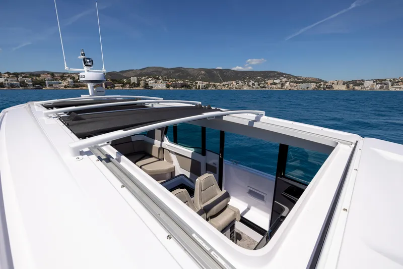  Yacht Photos Pics 2023 Axopar 45 Cross Cabine with open sunroof, cruising on clear blue waters.