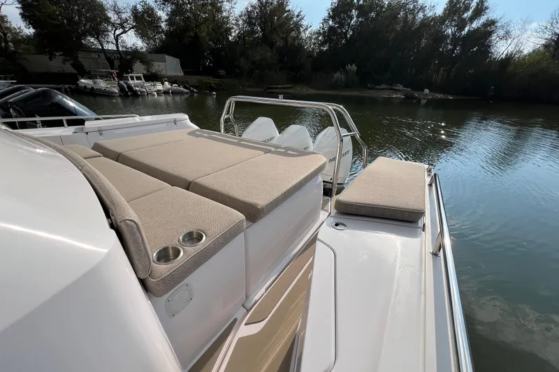  Yacht Photos Pics 2023 Axopar 45 Cross Cabine boat with cushioned seating, docked by a serene waterway.