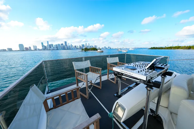 Finesse Yacht Photos Pics Azimut 68E yacht deck with DJ setup, overlooking city skyline and ocean, 2007 model.