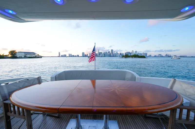 Finesse Yacht Photos Pics Azimut 68E 2007 yacht deck with wooden table, overlooking city skyline and water.