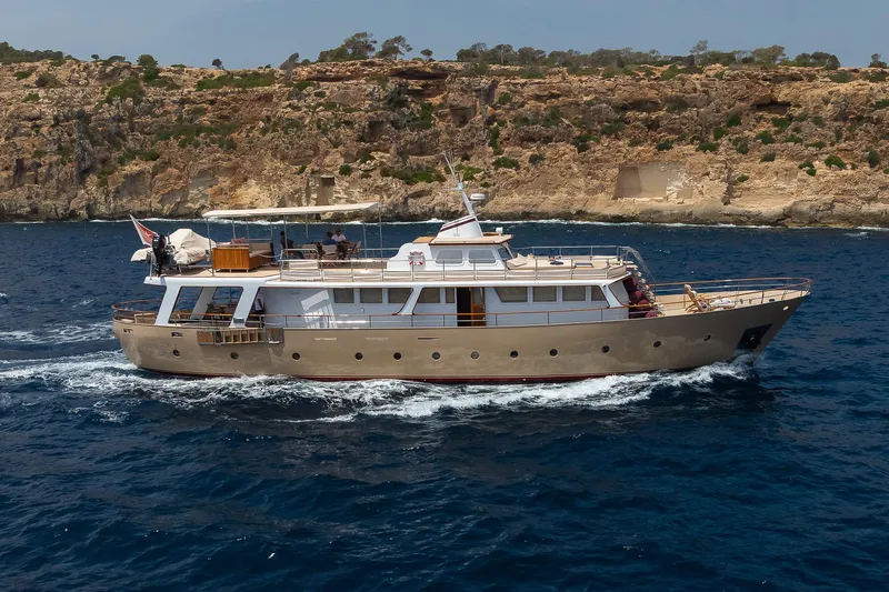 Black Pepper Yacht Photos Pics Vintage 1975 Lavagna round stern motoryacht cruising near rocky coastline.