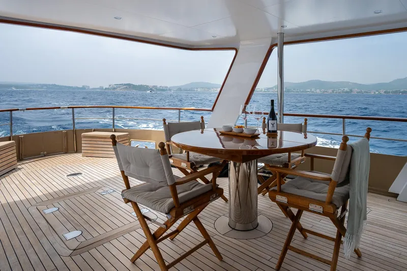 Black Pepper Yacht Photos Pics Lavagna 1975 round stern motoryacht deck with dining table, ocean view.