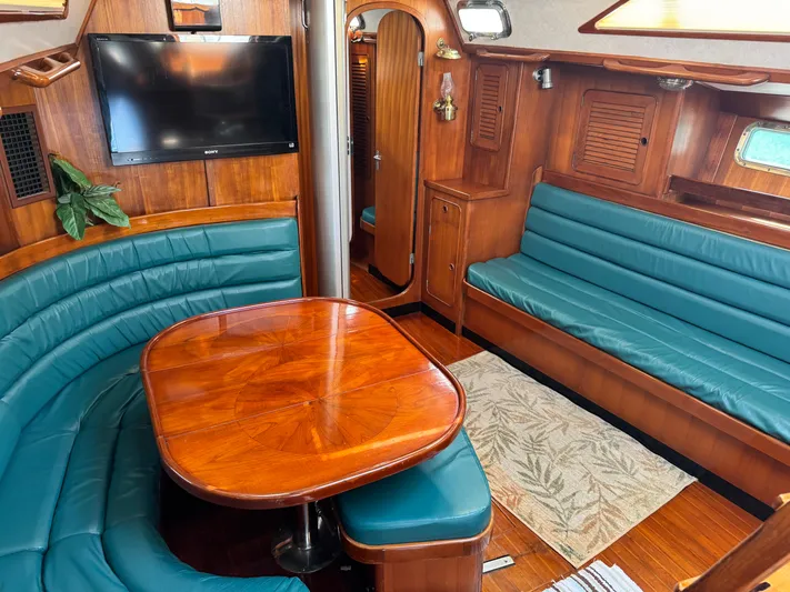 Dream Catcher Yacht Photos Pics Luxurious 1995 Hylas 46 yacht interior with wooden table, teal seating, and mounted TV.