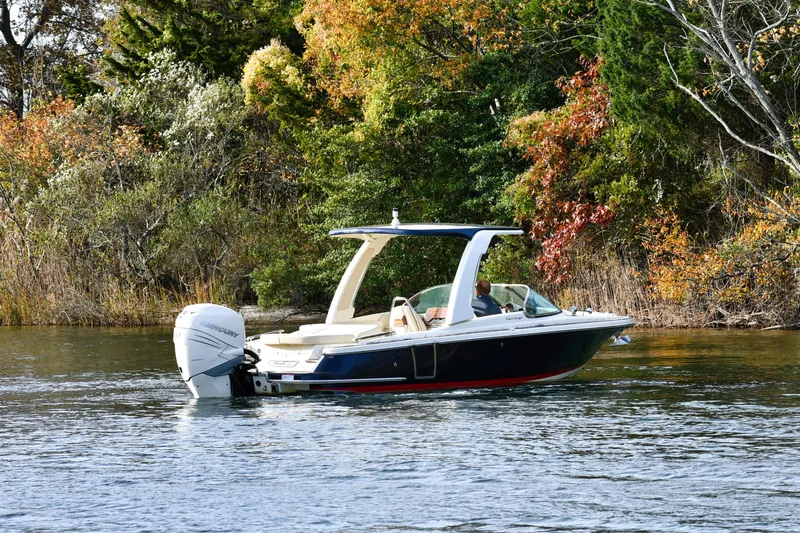  Yacht Photos Pics 2022 Chris-Craft Launch 25 GT boat cruising on a scenic lake with autumn foliage.