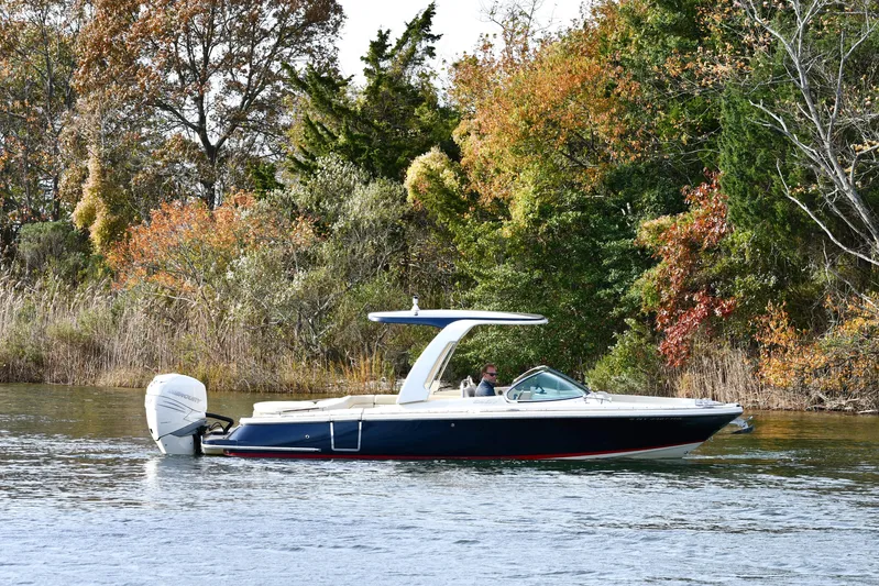  Yacht Photos Pics 2022 Chris-Craft Launch 25 GT boat cruising on a scenic lake with autumn foliage.
