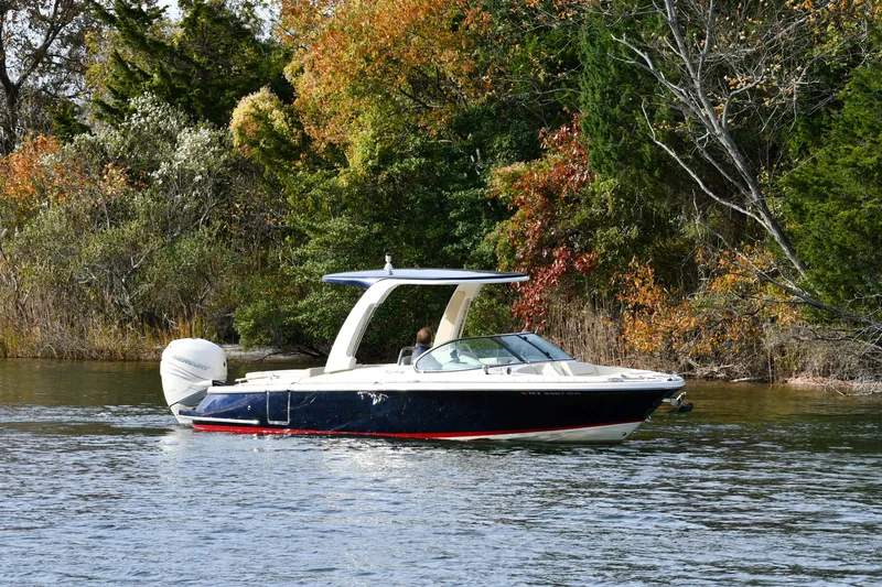  Yacht Photos Pics 2022 Chris-Craft Launch 25 GT boat cruising on a scenic lake with autumn foliage.