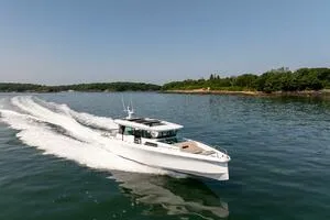 Stock 5 Yacht Photos Pics 2024 Axopar 45 boat cruising on a calm lake with lush green shoreline.