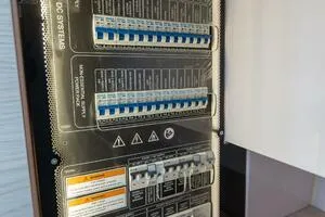 Stock 5 Yacht Photos Pics Electrical panel on a 2024 Axopar 45 boat, featuring circuit breakers and safety labels.