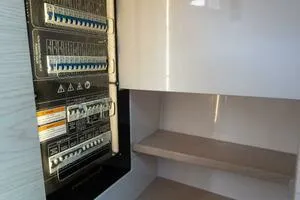 Stock 5 Yacht Photos Pics Electrical panel inside 2024 Axopar 45 boat, showcasing circuit breakers and storage shelves.