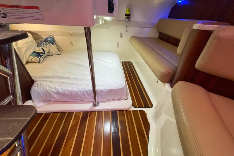  Yacht Photos Pics 2010 Pursuit OS 375 Offshore cabin with bed, seating, and wooden flooring.