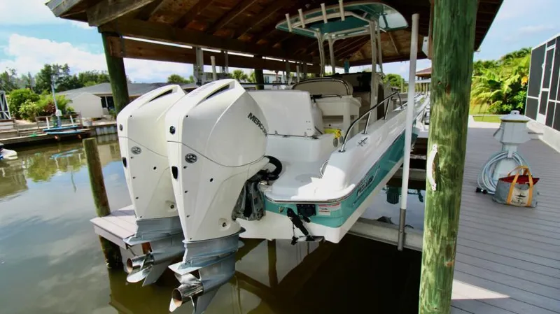 Yacht Photos Pics 2019 Boston Whaler DAUNTLESS boat with dual engines docked under a wooden canopy.