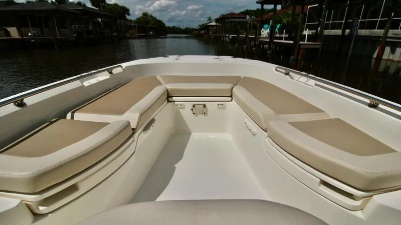  Yacht Photos Pics 2019 Boston Whaler DAUNTLESS boat interior with cushioned seating, docked on a calm waterway.