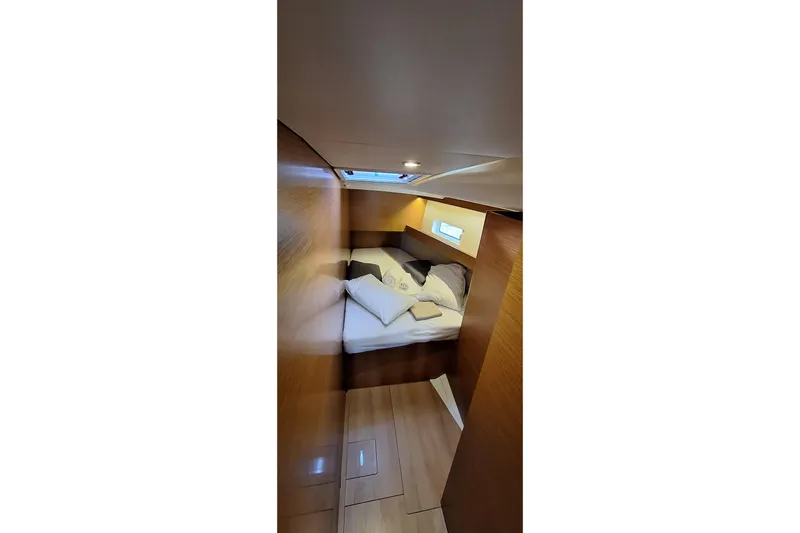  Yacht Photos Pics Cozy cabin interior of 2019 Jeanneau Sun Odyssey 490 sailboat with bed and wooden finish.