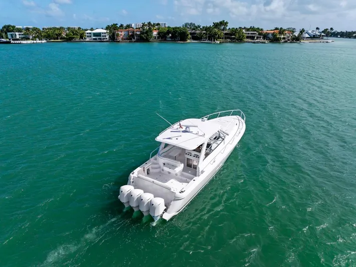  Yacht Photos Pics 2018 Intrepid 475 Sport Yacht cruising on turquoise waters near a coastal neighborhood.