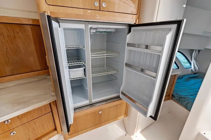  Yacht Photos Pics Open refrigerator in 2018 Intrepid 475 Sport Yacht, showcasing spacious interior and wooden cabinetry.