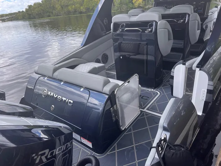  Yacht Photos Pics 2024 Mystic Powerboats M3800 interior with luxurious seating and sleek design on a calm waterway.