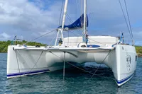 2013 Nautitech 542 catamaran anchored on calm water with lush greenery in the background.