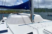 2013 Nautitech 542 catamaran with blue sail, docked in scenic harbor.