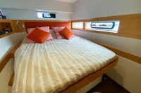 Cozy bedroom in 2013 Nautitech 542 yacht with striped bedding and orange pillows.