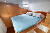 Cozy bedroom in 2013 Nautitech 542 yacht with blue bedding and wooden accents.