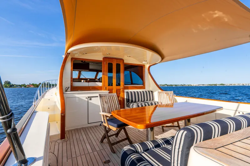 Pitt Stop Yacht Photos Pics 2020 Palm Beach Motor Yachts PB55, elegant deck with striped seating and wooden table, ocean view.