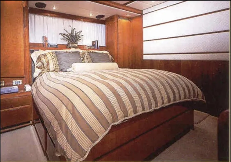  Yacht Photos Pics Luxurious bedroom interior on 1993 Tecnomarine yacht, featuring elegant wood paneling and striped bedding.