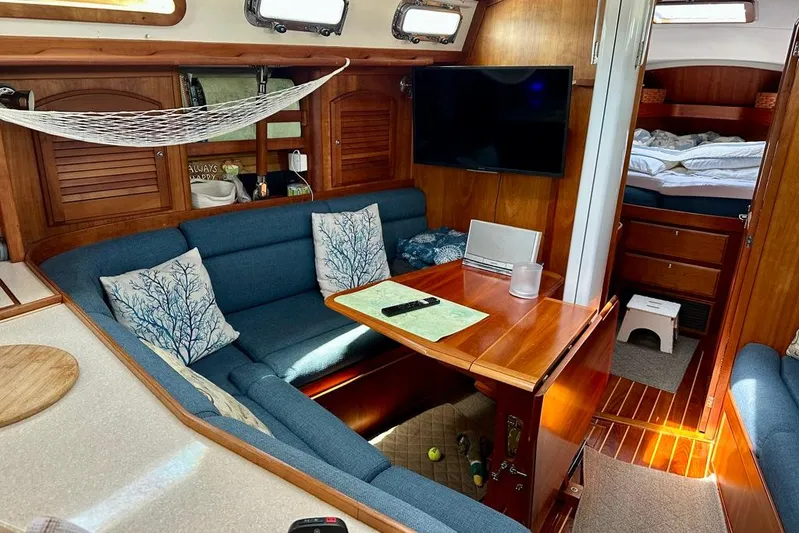  Yacht Photos Pics Cozy interior of 2002 Sabre 402 sailboat with blue seating, wooden table, and TV.