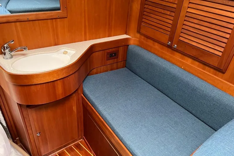  Yacht Photos Pics 2002 Sabre 402 yacht interior with wooden cabinetry, blue cushioned seating, and a compact sink.