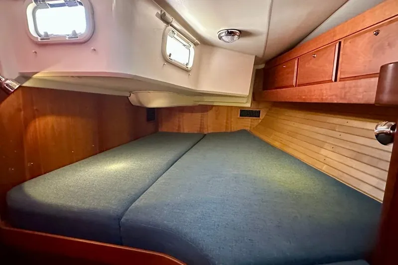  Yacht Photos Pics Cozy cabin interior of 2002 Sabre 402 sailboat with wooden cabinetry and blue cushions.