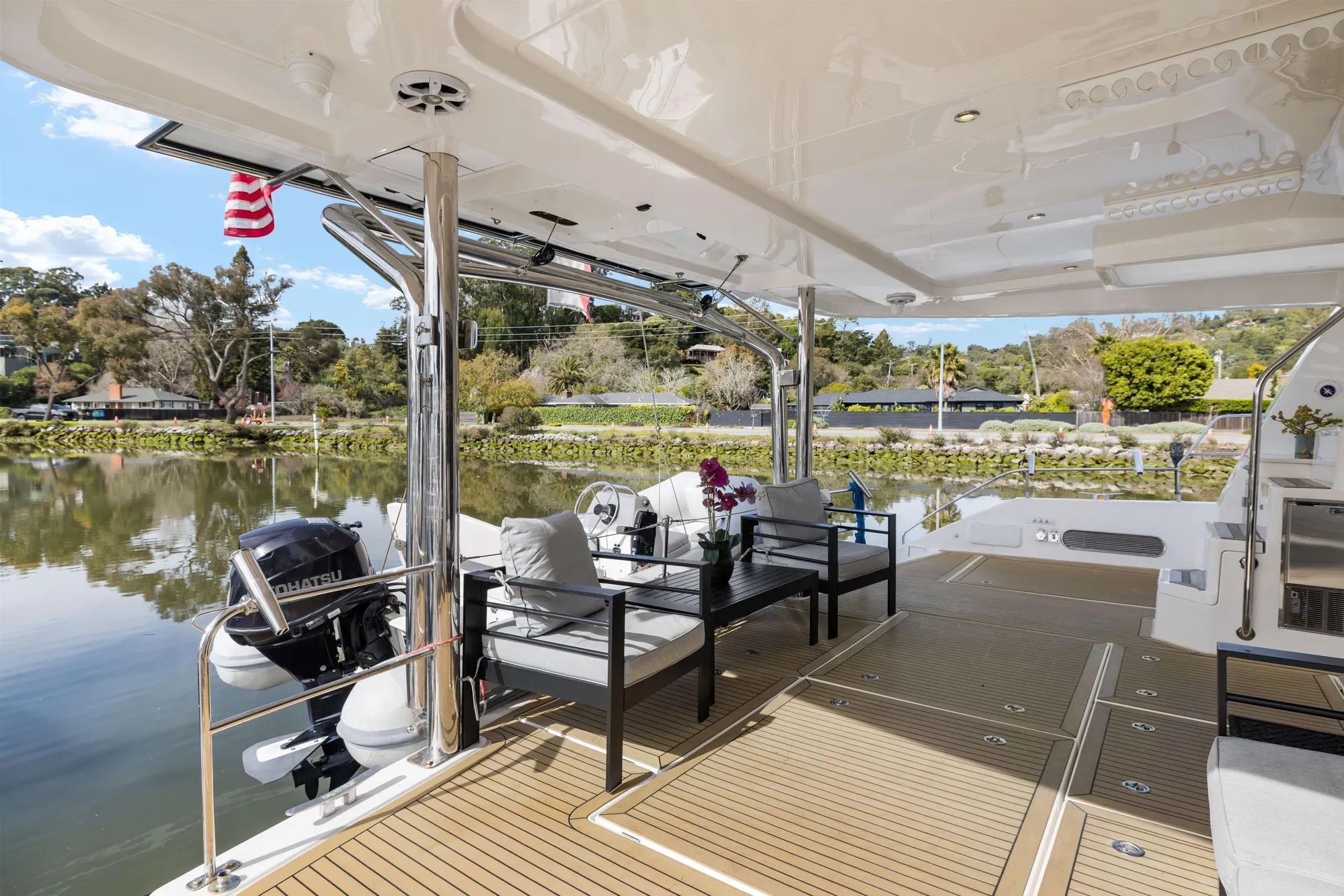 Luxurious 2015 Leopard 58 yacht deck with seating, overlooking serene waters and lush greenery.