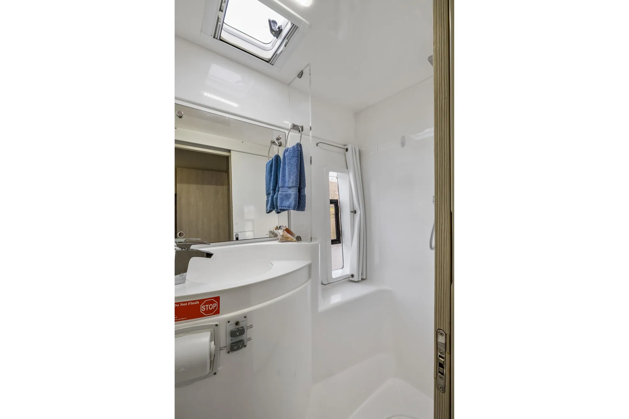 Compact bathroom in 2015 Leopard 58 yacht with skylight and blue towels.