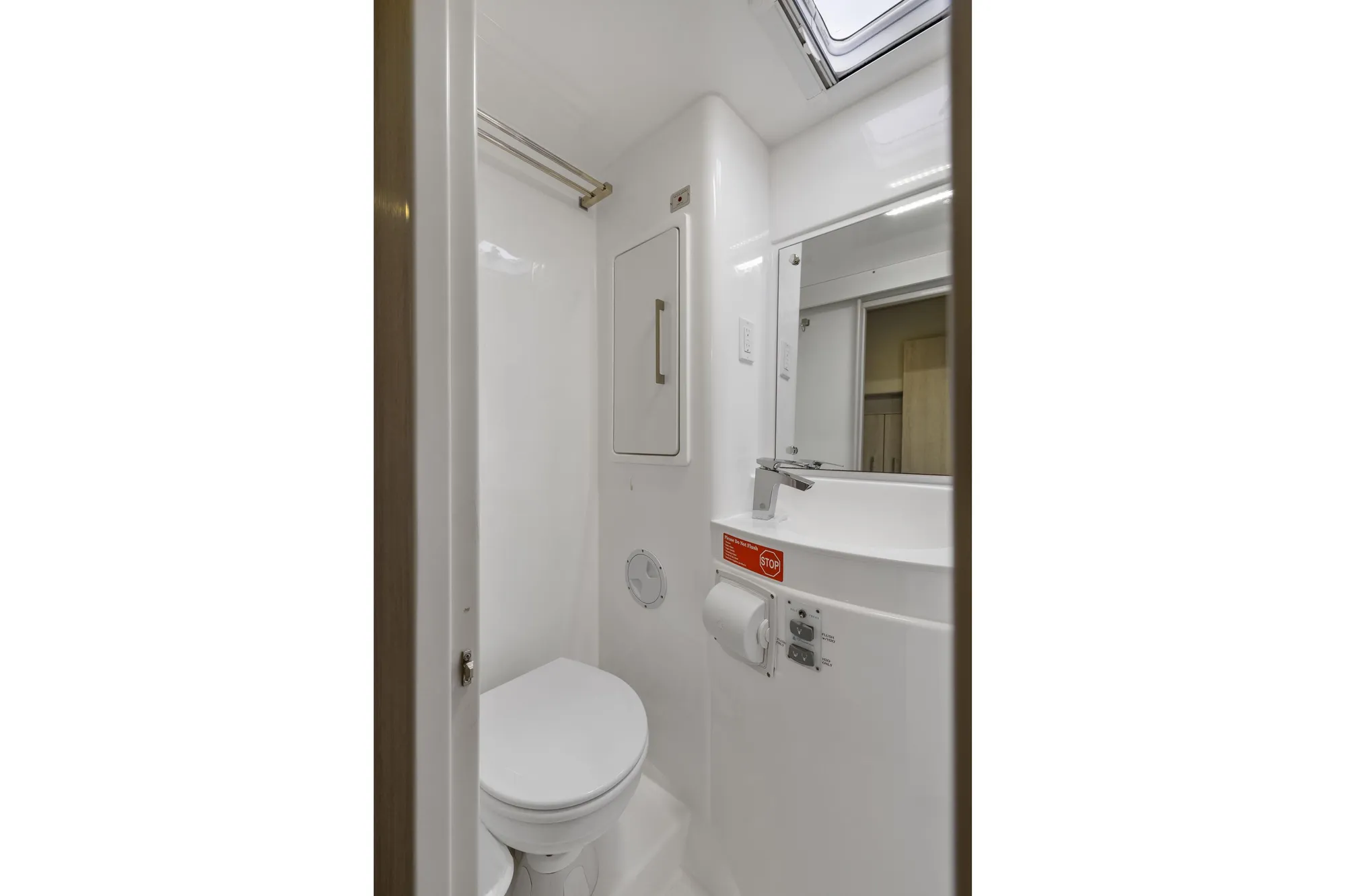 Compact bathroom in 2015 Leopard 58 yacht, featuring toilet, mirror, and storage.
