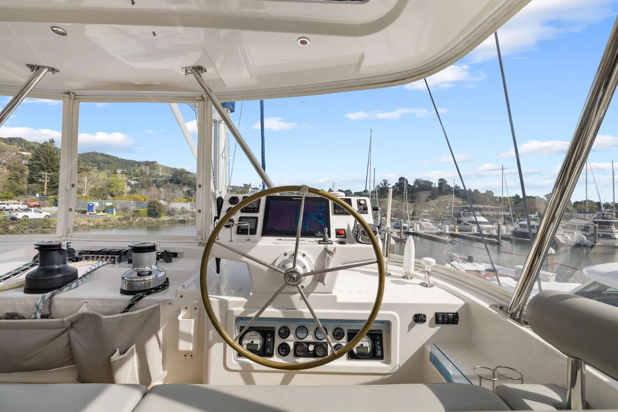 Helm of 2015 Leopard 58 yacht with steering wheel and navigation equipment, docked at marina.