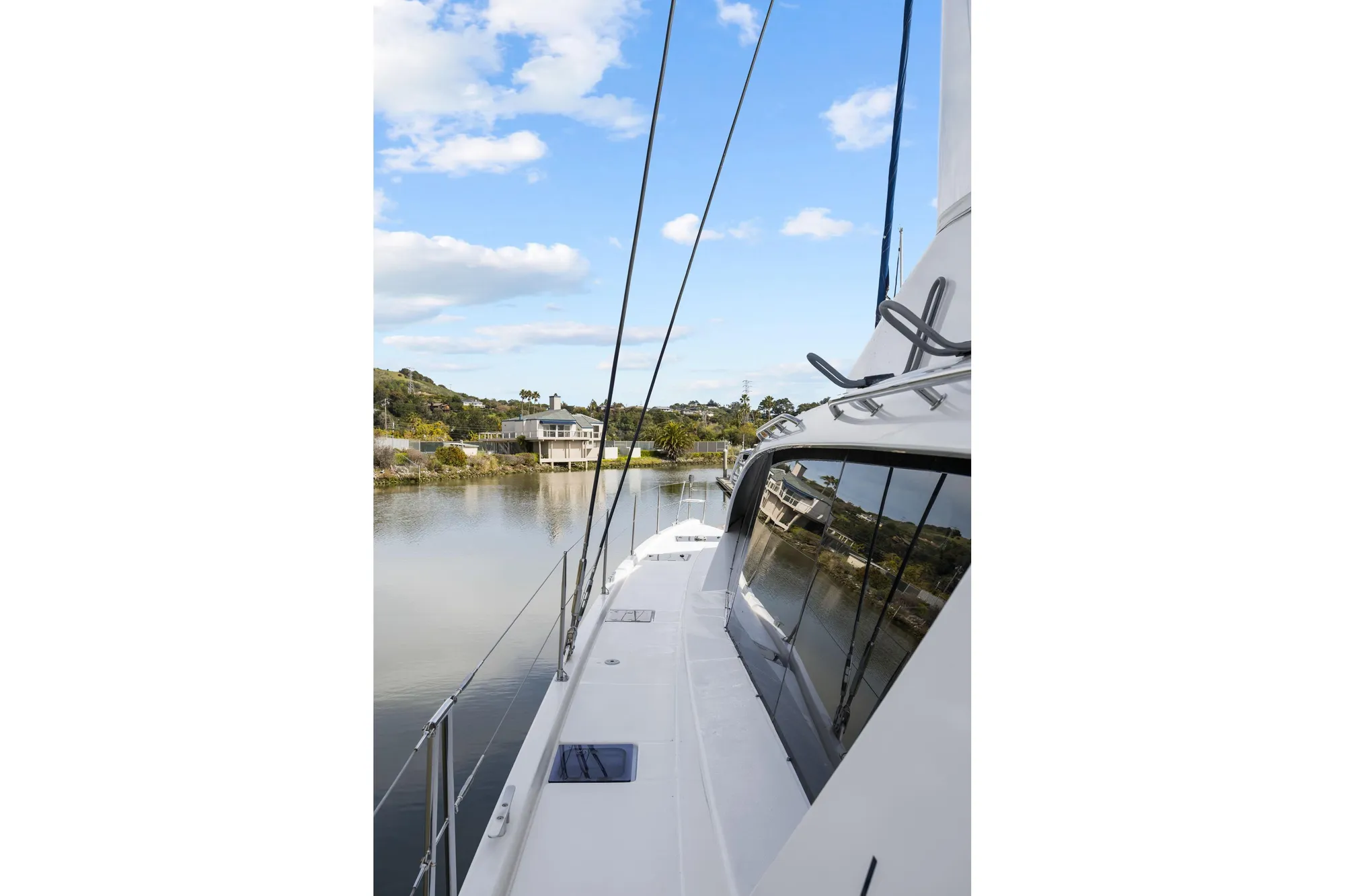 2015 Leopard 58 yacht on calm water, clear sky, and scenic shoreline view.