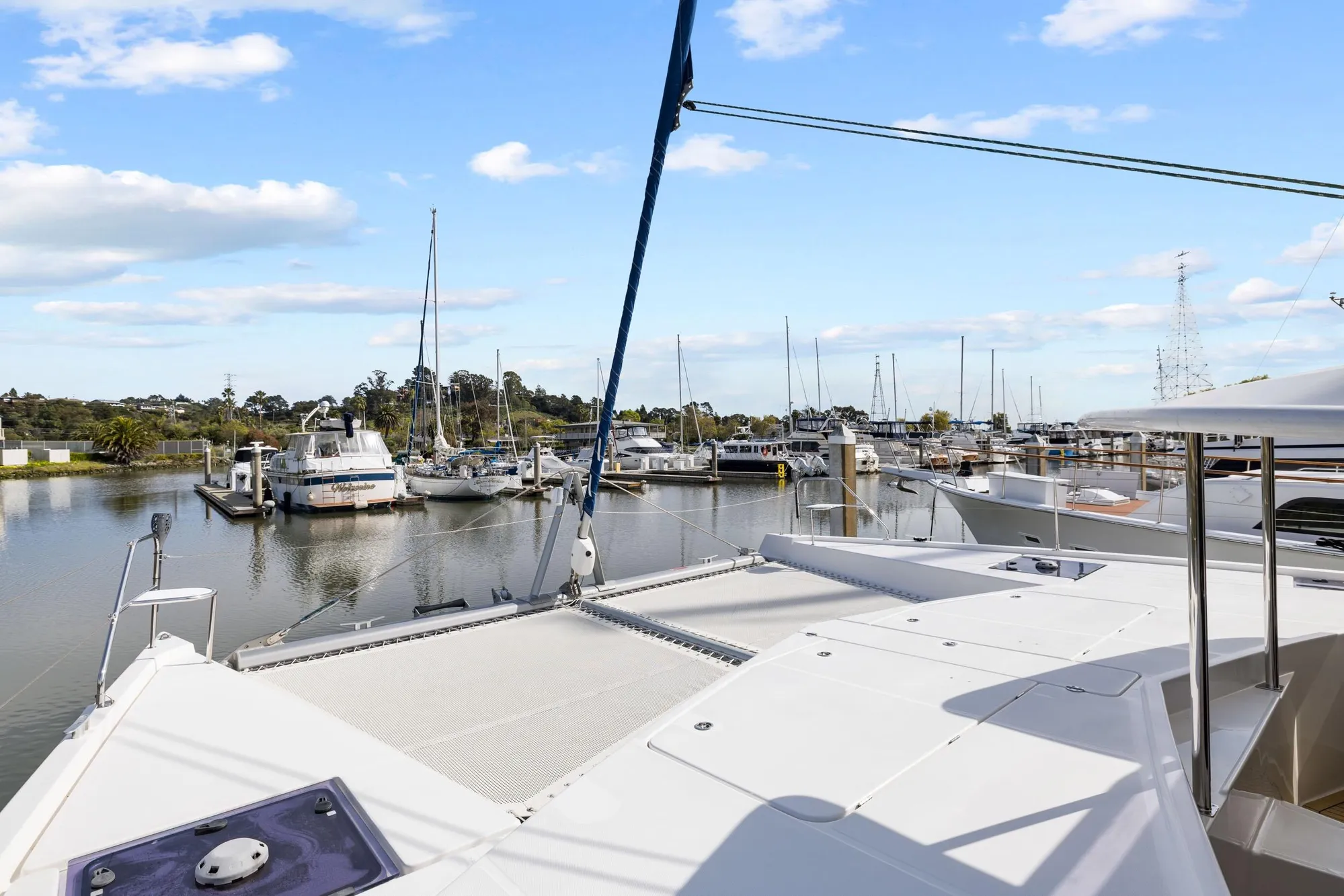 2015 Leopard 58 yacht docked at marina, surrounded by sailboats under a clear blue sky.