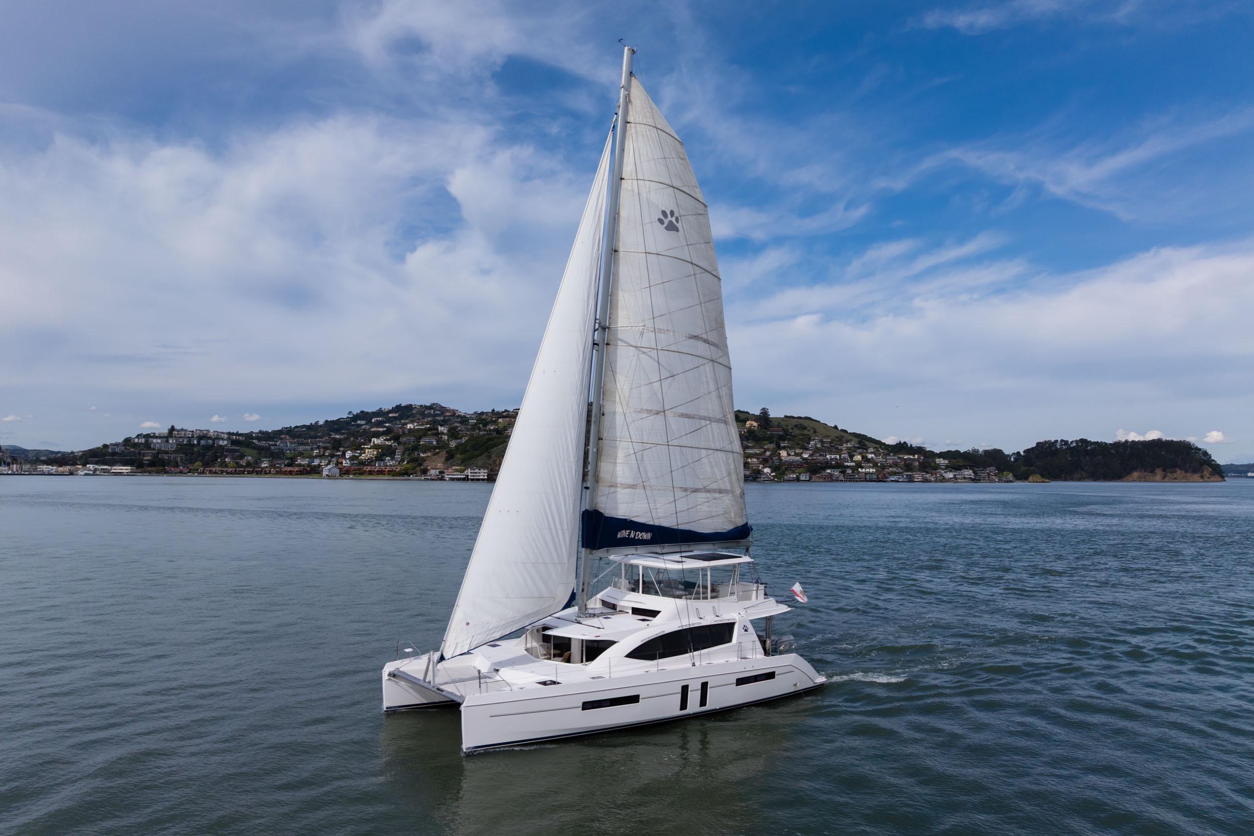 Sailing catamaran Leopard 58, 2015 model, cruising on calm waters under a clear sky.