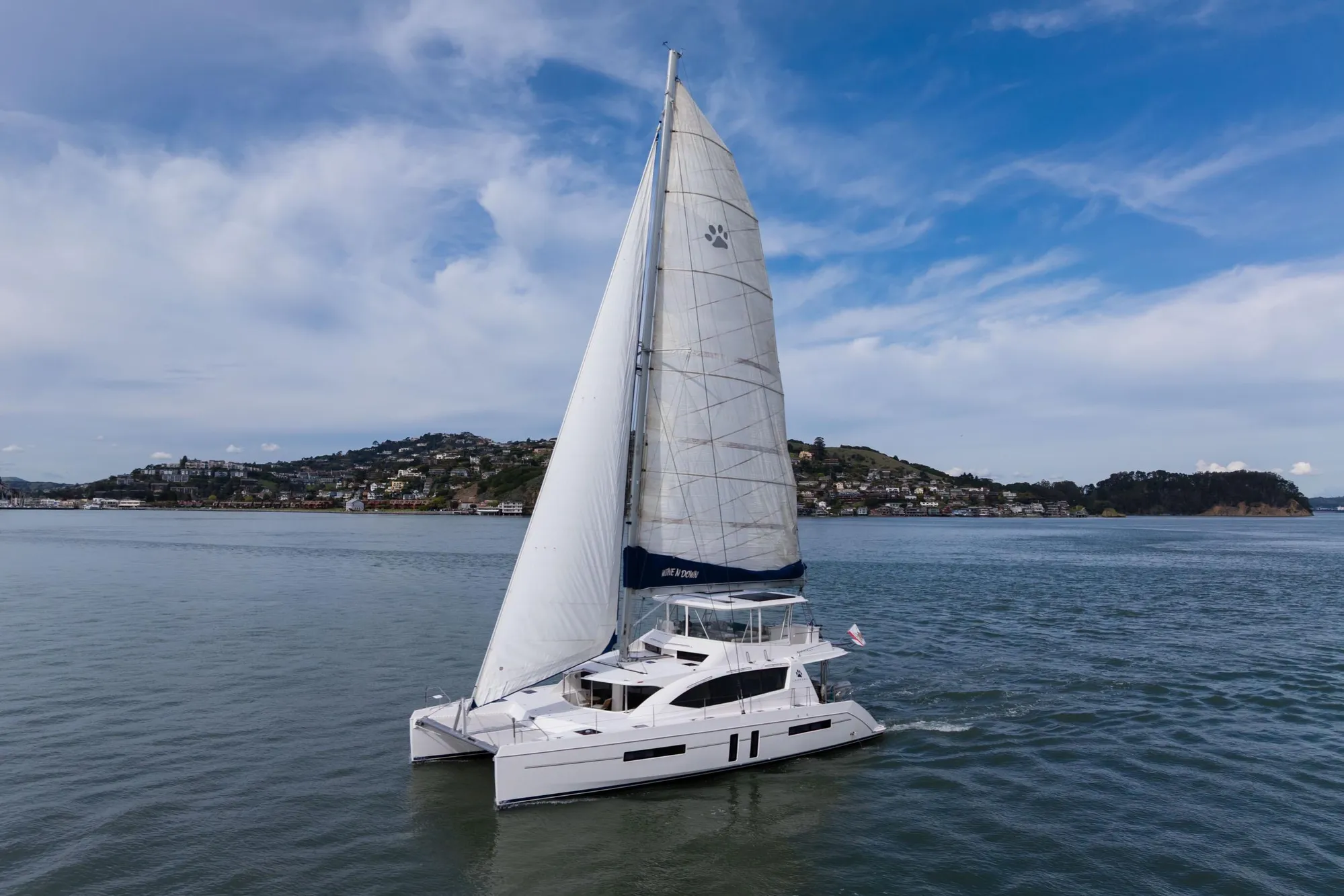 Sailing catamaran Leopard 58, 2015 model, cruising on calm waters under a clear sky.