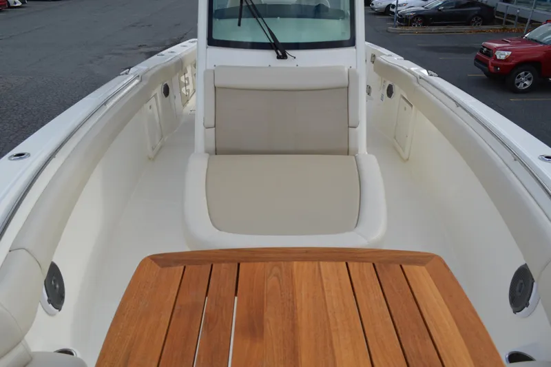  Yacht Photos Pics 2018 Boston Whaler 330 Outrage boat interior with cushioned seating and wooden table.