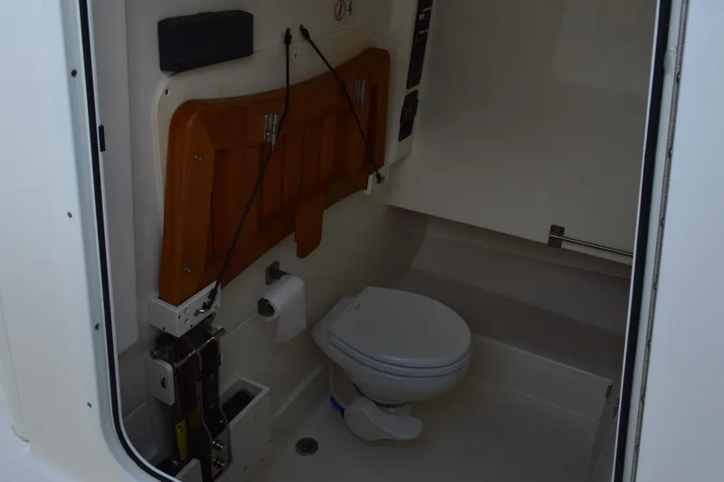  Yacht Photos Pics Interior of 2018 Boston Whaler 330 Outrage boat bathroom with toilet and wooden accents.