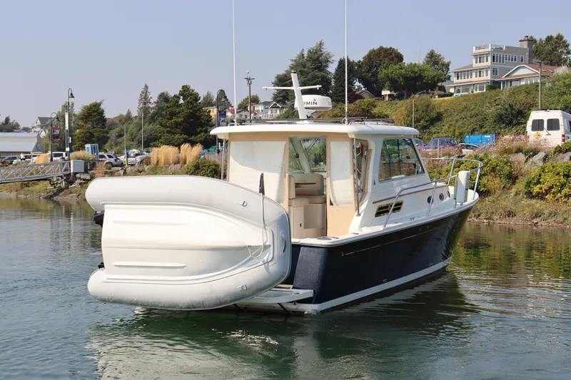 Naut On Call Yacht Photos Pics 2016 Back Cove 34 boat docked with inflatable dinghy attached, scenic waterfront background.