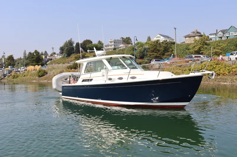 Naut On Call Yacht Photos Pics 2016 Back Cove 34 boat cruising near a scenic shoreline.