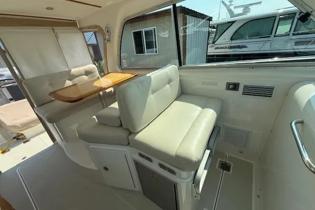 Naut On Call Yacht Photos Pics Interior of a 2016 Back Cove 34 boat with cushioned seating and a wooden table.