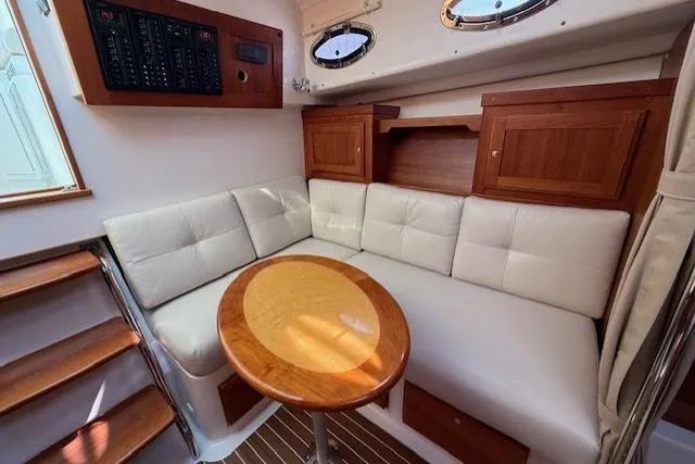 Naut On Call Yacht Photos Pics Interior of 2016 Back Cove 34 yacht with cushioned seating and wooden table.