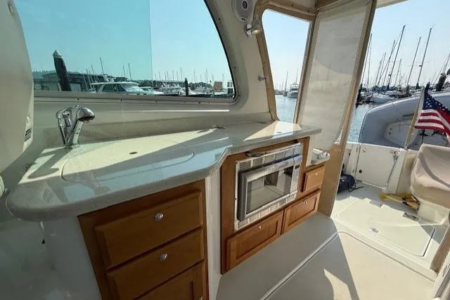 Naut On Call Yacht Photos Pics 2016 Back Cove 34 yacht interior with kitchenette, featuring sink, microwave, and wooden cabinetry.