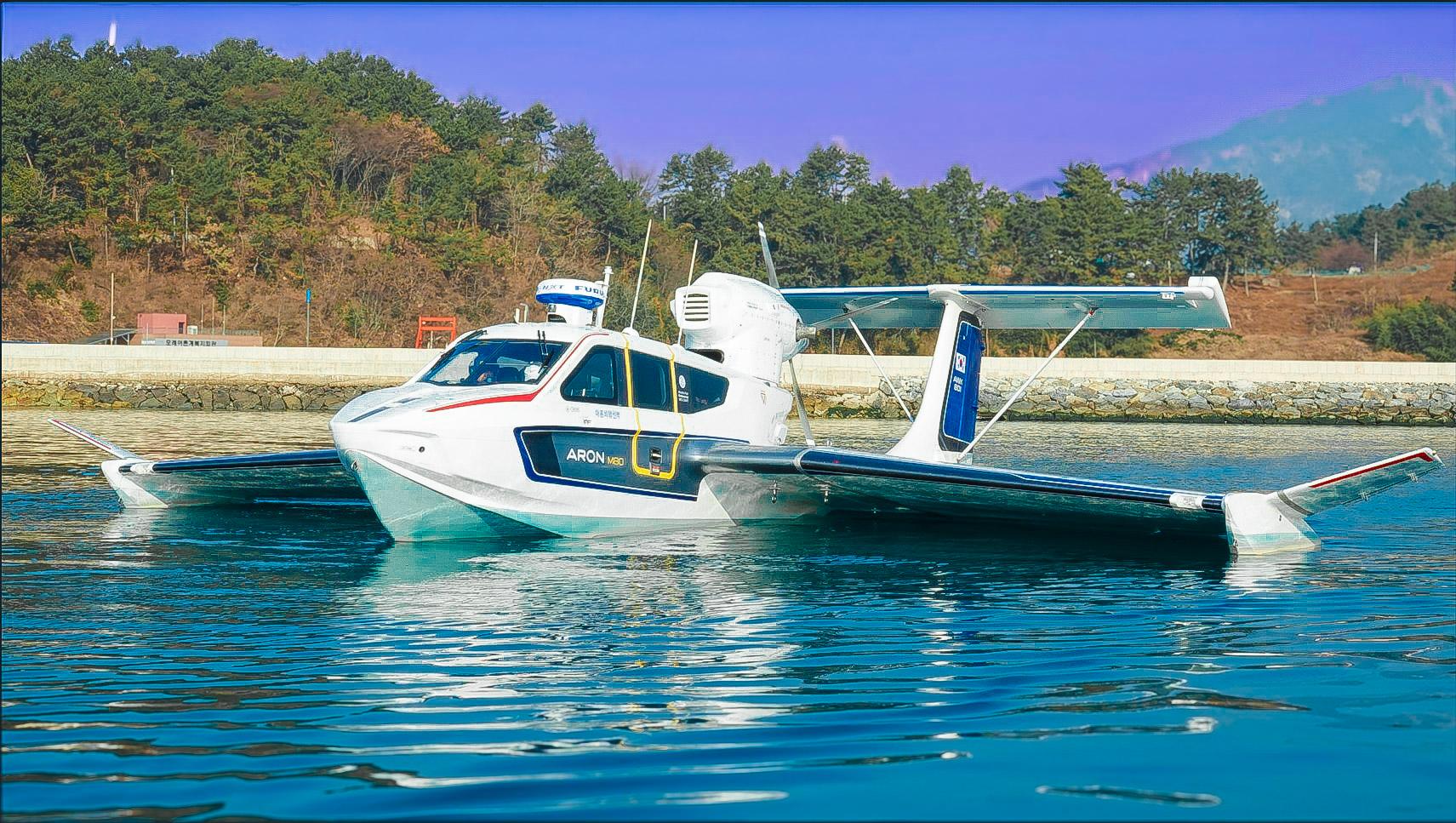 Seaplane Aron M 80, 2025 model, floating on calm water near a forested shoreline.