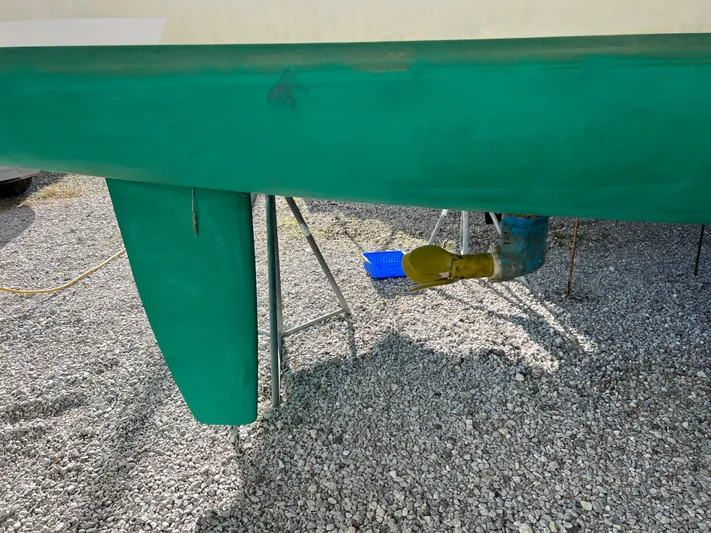 Trebuchet Yacht Photos Pics Green hull of a 2000 Switch 51 catamaran on gravel, showing rudder and propeller.