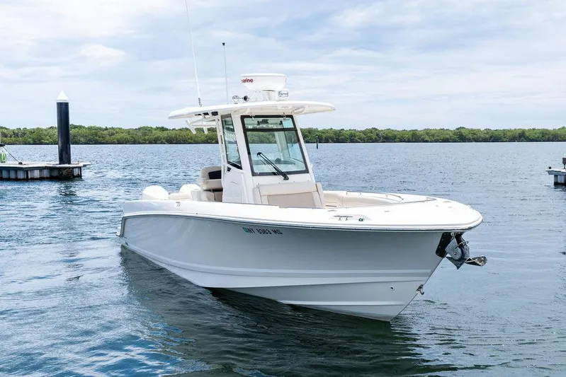 Zoom Yacht Photos Pics 2022 Boston Whaler 280 Outrage boat on calm water near a dock.